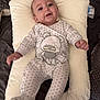 baby, infant, pillow, onesie, polka_dot, teddy_bear, cute, smiling, lying_down, soft_fabric, indoor, child, adorable, happy, comfortable, small_hands, bed, blanket, face, portrait