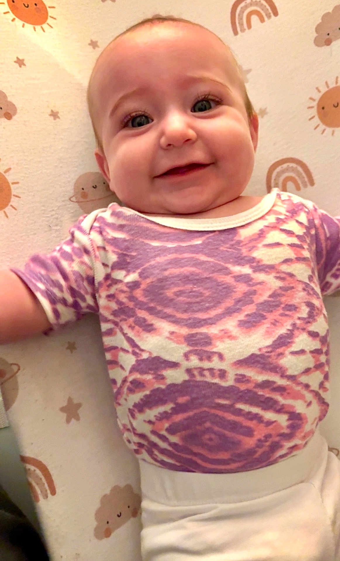 Ainsley joined the competition — help win amazing prizes! baby, smiling, infant, child, patterned_shirt, purple, pink, cute_blanket, sun, cloud, star, rainbow, lying_down, happy, face, portrait, indoor, person, soft_lighting, closeup
