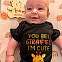 baby, infant, smiling, black_shirt, giraffe, cute, lying_down, four_months, patterned_blanket, sun, rainbow, cloud, wooden_sign, happy, child, face, eyes, cute_clothing, baby_gesture, indoor
