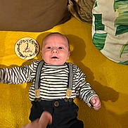 Axel participe au concours pour gagner de l'argent avec cette photo : baby, infant, striped_shirt, suspenders, yellow_blanket, plaque, 2_months, hand, person, lying_down, smile, face, clothing, indoor, cute, young_child, portrait, child, newborn, soft_texture