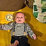 baby, infant, striped_shirt, suspenders, yellow_blanket, plaque, 2_months, hand, person, lying_down, smile, face, clothing, indoor, cute, young_child, portrait, child, newborn, soft_texture