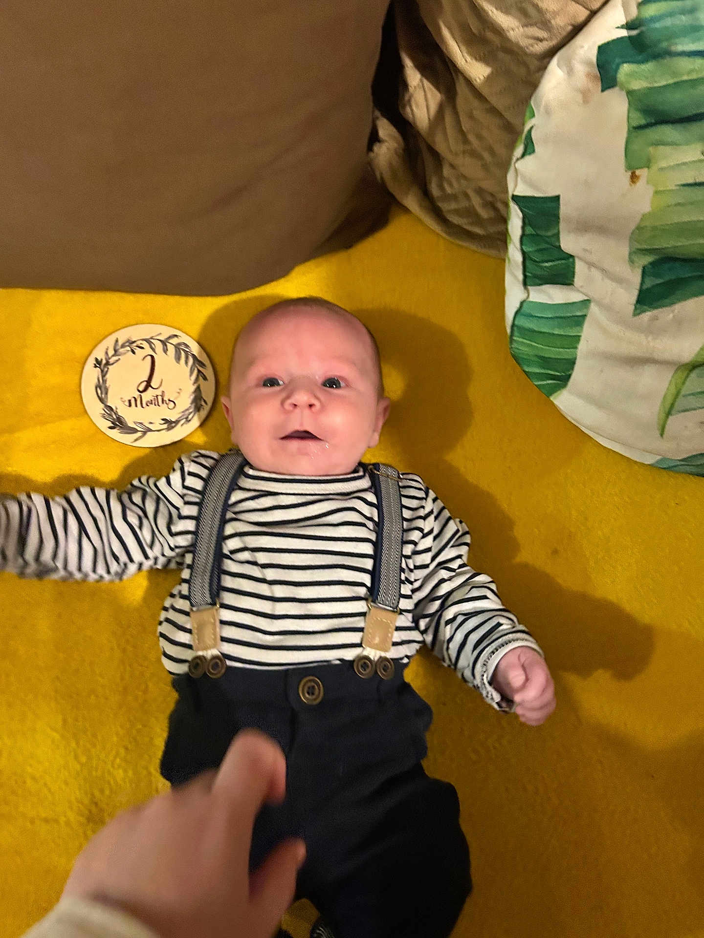 Axel participe au concours pour gagner de l'argent avec cette photo : baby, infant, striped_shirt, suspenders, yellow_blanket, plaque, 2_months, hand, person, lying_down, smile, face, clothing, indoor, cute, young_child, portrait, child, newborn, soft_texture