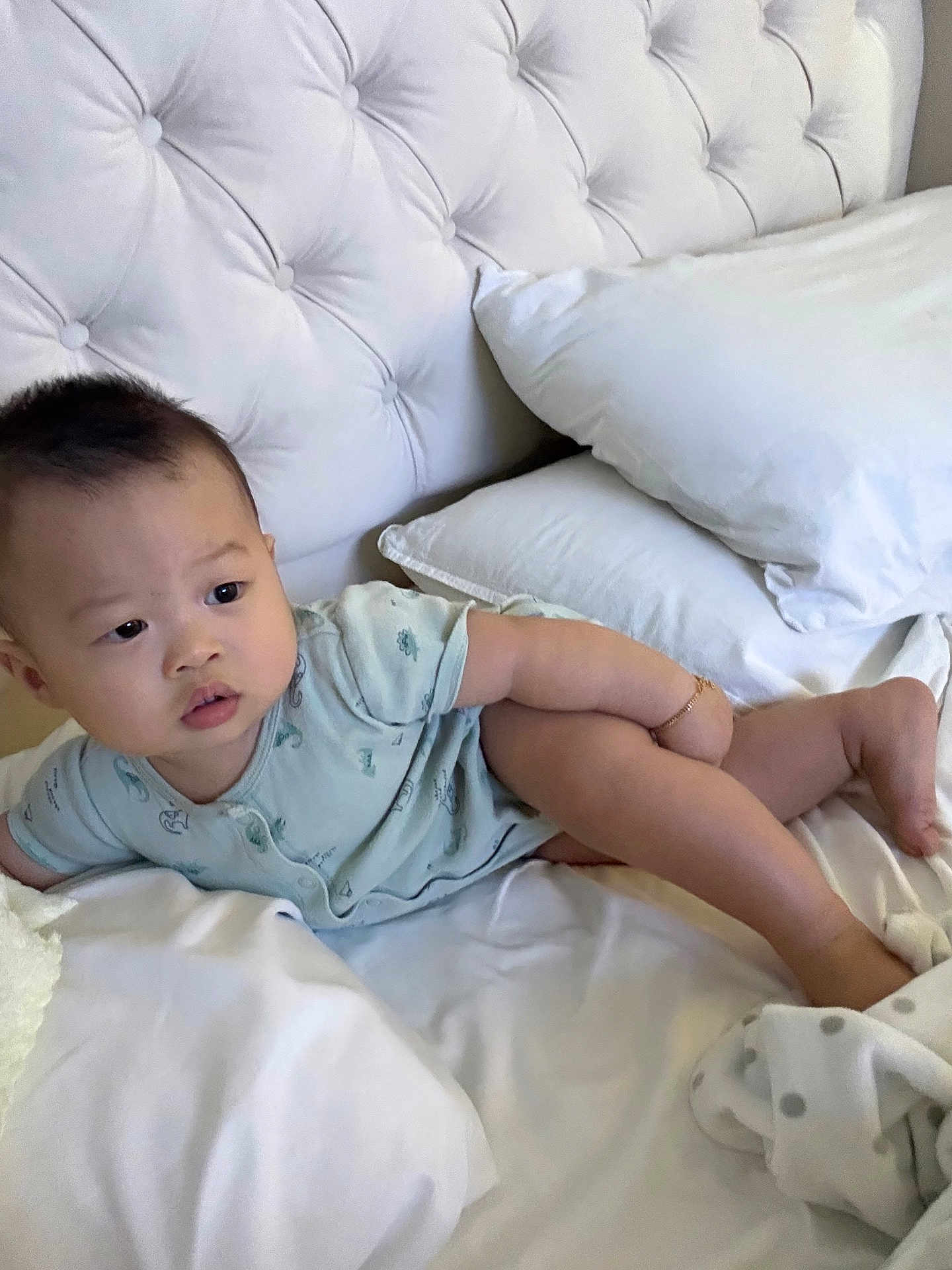 Tristan joined the competition — help win amazing prizes! baby, child, infant, bed, pillow, blanket, white, clothing, onesie, skin, head, face, expression, arm, leg, foot, indoor, soft, curious, relaxed
