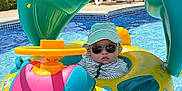 Tristan joined the competition — help win amazing prizes! baby, child, pool, inflatable, float, sunglasses, hat, water, summer, sunlight, outdoor, swimming_pool, toy, colorful, fun, vacation, leisure, sun_protection, relaxation, floating