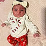 baby, infant, child, headband, bow, pajamas, holiday, christmas, candy_cane, heart, red_pants, white_sweater, blanket, soft_texture, lying_down, cute, portrait, indoors, smiling, festive