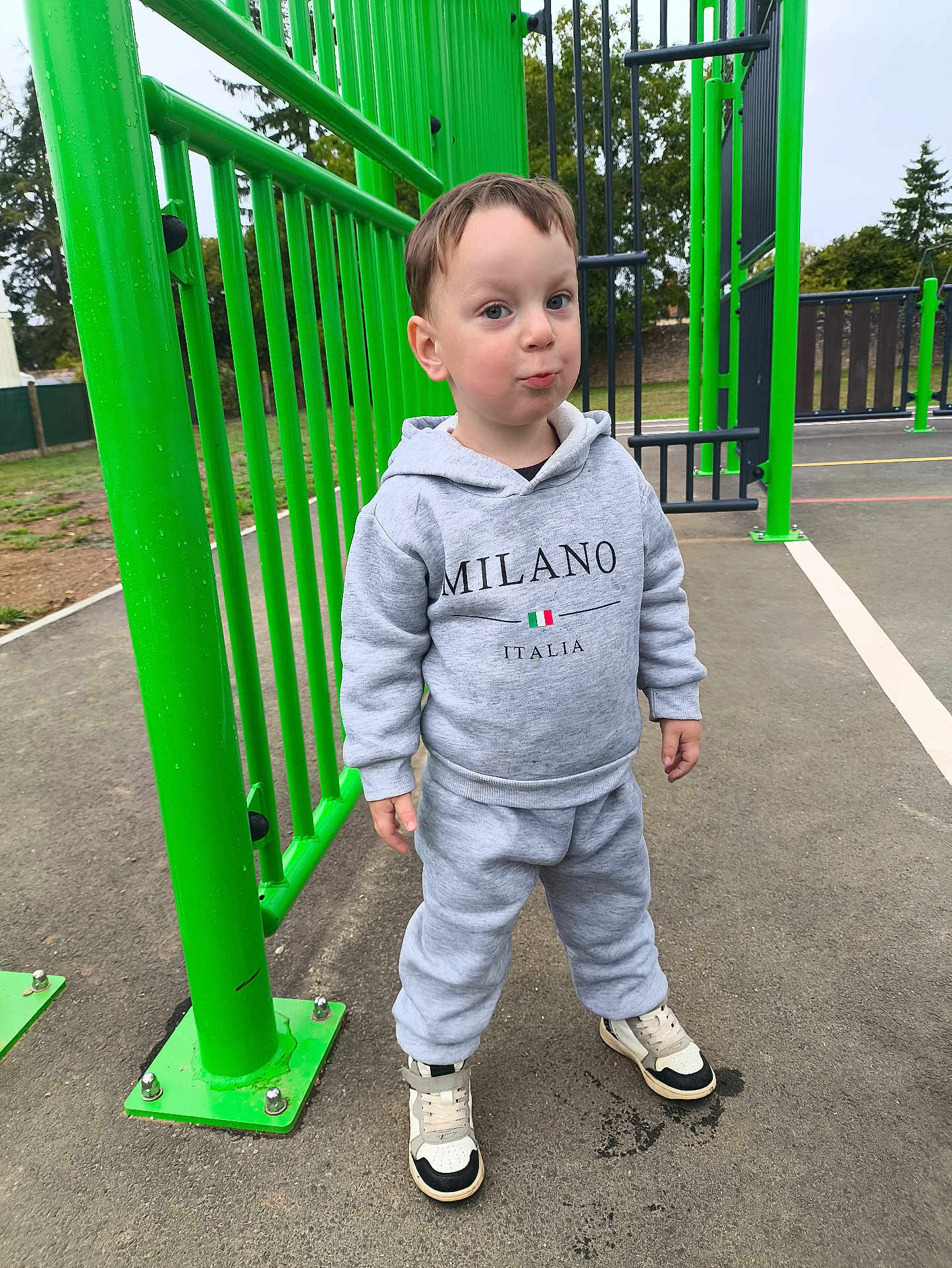Heimdall participe au concours pour gagner de l'argent avec cette photo : child, playground, green, sportswear, hoodie, sneakers, outdoor, smile, person, park, young, casual, concrete, fence, trees, daytime, cute, standing, fun, expression