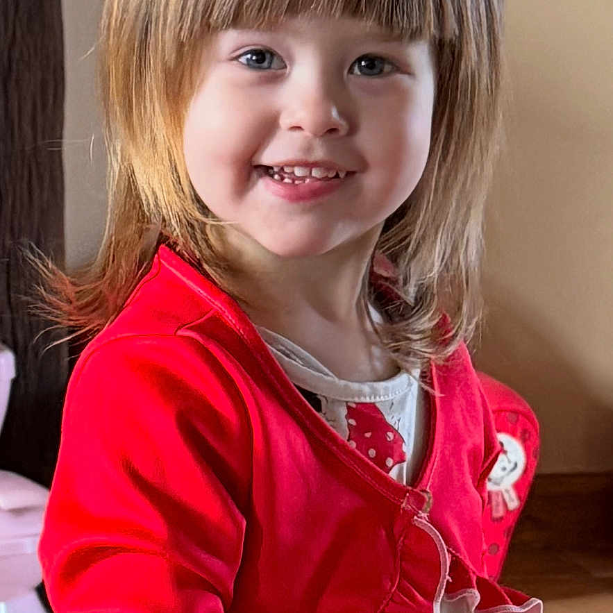 Eléana Hita Cortes a rejoint le concours — aidez-le/la à gagner de superbes lots ! child, smiling, indoor, red_jacket, dress, portrait, face, hair, young_child, happy, person, fashion, cute, standing, floor, wood, light, casual, girl, clothing