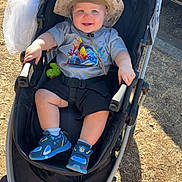 Elijah is registered to the contest to win money with this photo: baby, blue, car, casual, child, drink_tumbler, grass, happy, hat, outdoor, person, seatbelt, shoes, shorts, smiling, stroller, sunlight, toddler, toy, tshirt