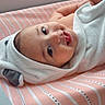 baby, smiling, towel, hooded_towel, pink, striped, changing_pad, infant, cute, happy, face, skin, lying_down, indoors, child, newborn, person, soft, cozy, portrait