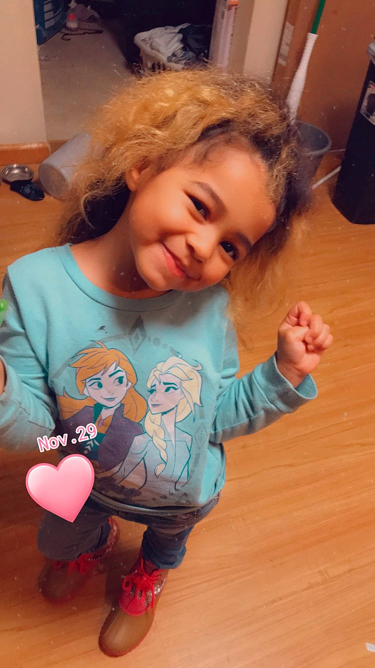 Khalani is registered to the contest to win money with this photo: arm, baby_toddler_clothing, cheek, flooring, gesture, hair, happy, head, joy, mammal, mouth, nose, organ, person, skin, sleeve, smile, t_shirt, thumb, toddler