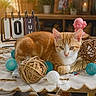 cat, orange_cat, table, decorative_balls, calendar, indoor, plants, framed_photos, wooden_furniture, cozy, relaxed, decor, vintage_calendar, white_tablecloth, orange_and_white, pet, cute, domestic_cat, home, resting