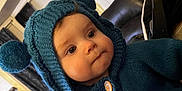 Alaina is registered to the contest to win money with this photo: baby, child, indoor, knitwear, hoodie, pom_poms, blue, face, portrait, seated, curious, buttoned, sweater, cozy, furniture, living_room, couch, window, curtains, person