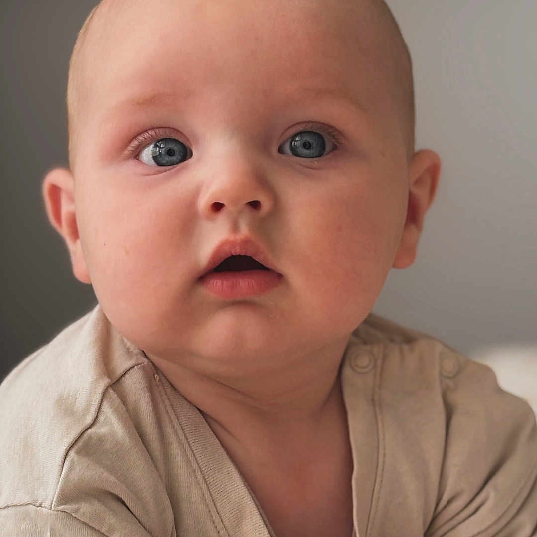 Louis a rejoint le concours — aidez-le/la à gagner de superbes lots ! baby, beige_clothing, blue_eyes, child, closeup, curious, cute, expression, eyes, face, hands, head, indoor, infant, person, portrait, skin, skin_texture, soft_light, young_child