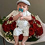 baby, infant, pacifier, cap, white_overalls, roses, bouquet, flowers, red_roses, green_leaves, hand, bracelet, cute, portrait, indoor, flower_arrangement, child, sitting, soft_lighting, neutral_background