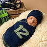 baby, beanie, blanket, cozy, cushion, helmet, indoor, infant, knitwear, number_12, peaceful, portrait, resting, scarf, seattle_seahawks, sleeping, soft, sports, swaddled, wooden_crate