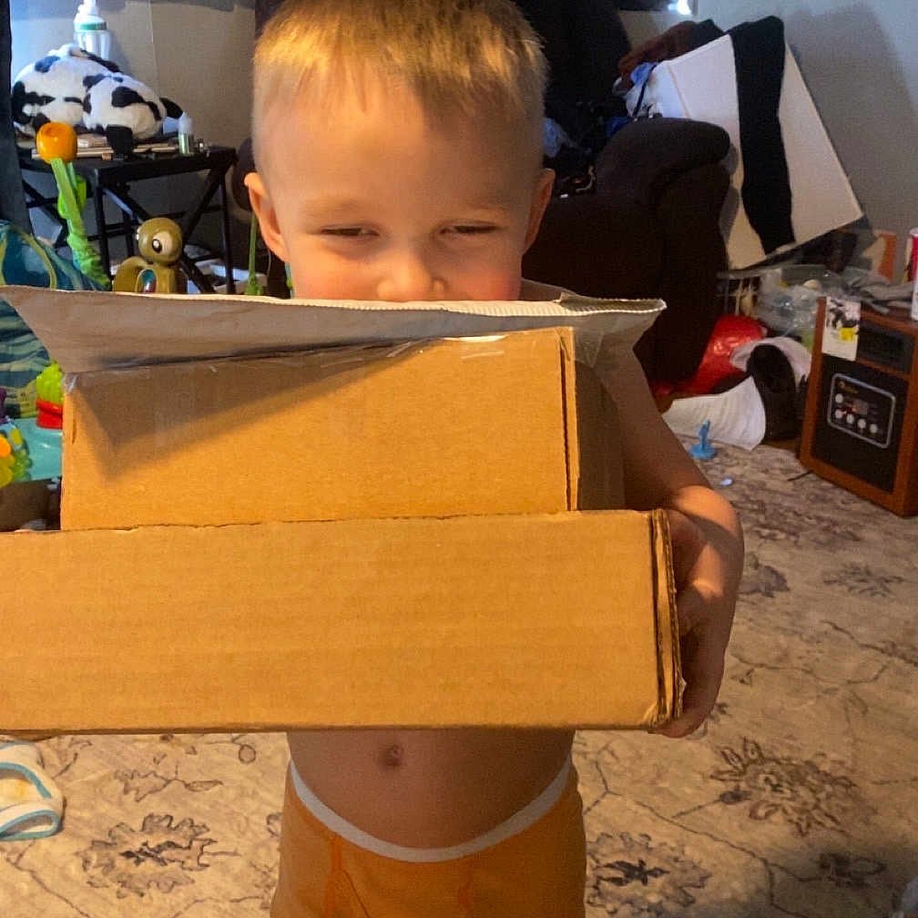Kane is registered to the contest to win money with this photo: architecture, baby, box, building, cardboard, clothing, costume, door, face, furniture, head, indoors, livingroom, person, photography, plant, portrait, pottedplant, shorts, wood
