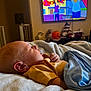 baby, sleeping, blanket, bed, yellow_shirt, indoor, television, animation, cartoon, cozy, child, peaceful, portrait, relaxation, home, comfort, infant, soft, cute, napping