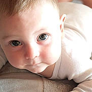Eden participe au concours pour gagner de l'argent avec cette photo : apparel, baby, child, closeup, curious, cute, expression, eyes, face, hand, indoors, infant, lying_down, newborn, person, portrait, skin, sleeve, soft_lighting, toddler