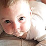 apparel, baby, child, closeup, curious, cute, expression, eyes, face, hand, indoors, infant, lying_down, newborn, person, portrait, skin, sleeve, soft_lighting, toddler