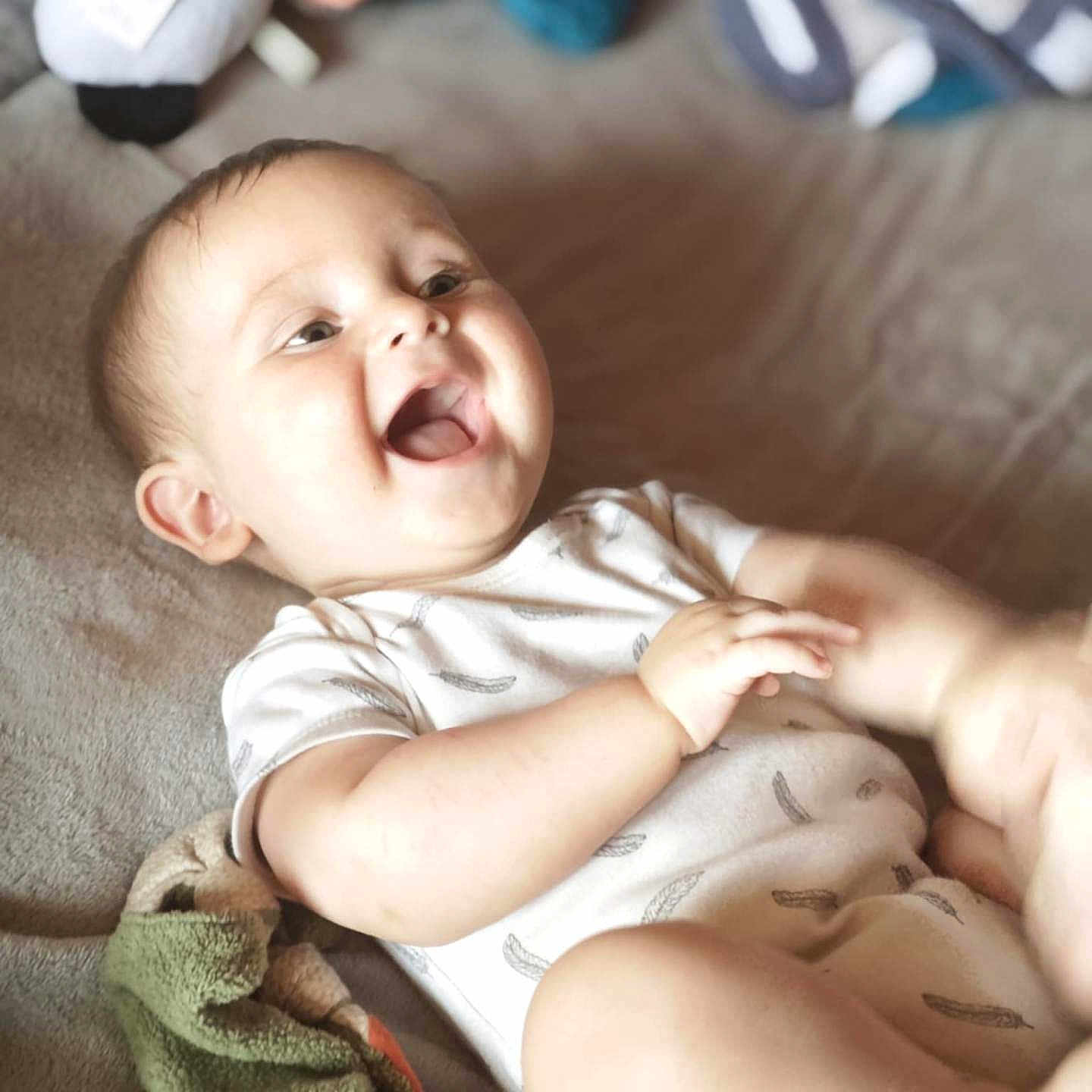 Eden participe au concours pour gagner de l'argent avec cette photo : baby, blanket, child, chubby_cheeks, cozy, cute, expression, face, hand, happy, indoors, infant, laughing, lying_down, onesie, playful, relaxation, skin, smile, soft_toy