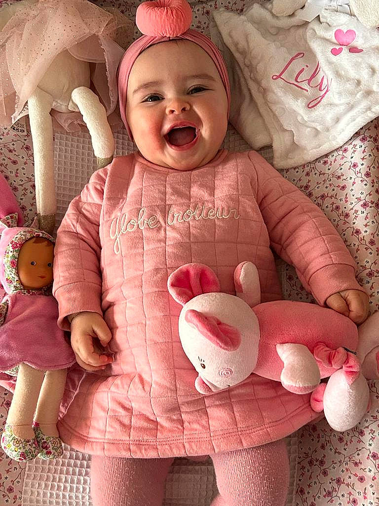 Lily participe au concours pour gagner de l'argent avec cette photo : arm, baby_toddler_clothing, cheek, eye, facial_expression, gesture, hand, happy, head, headwear, human, lip, mouth, nose, organ, person, pink, skin, sleeve, smile