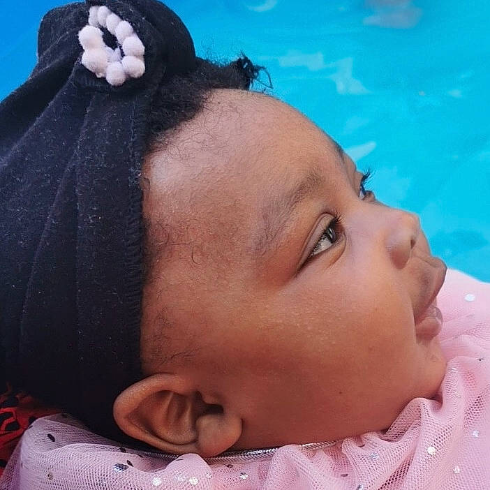 Dialla participe au concours pour gagner de l'argent avec cette photo : baby, black_hair, cheek, child, ear, face, fashion_accessory, forehead, hair, hair_accessory, head, mouth, neck, nose, person, pink, skin, toddler