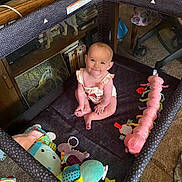 Madison joined the competition — help win amazing prizes! baby, playpen, toy, colorful_toy, smiling, indoor, carpet, furniture, child, cute, sitting, happy, person, plush_toy, living_room, floor, crawling_area, infant, home, playtime