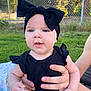baby, black_clothing, blue_eyes, bow, casual, child, cute, daylight, face, fence, grass, hand, headband, holding, infant, outdoor, person, portrait, skin, summer