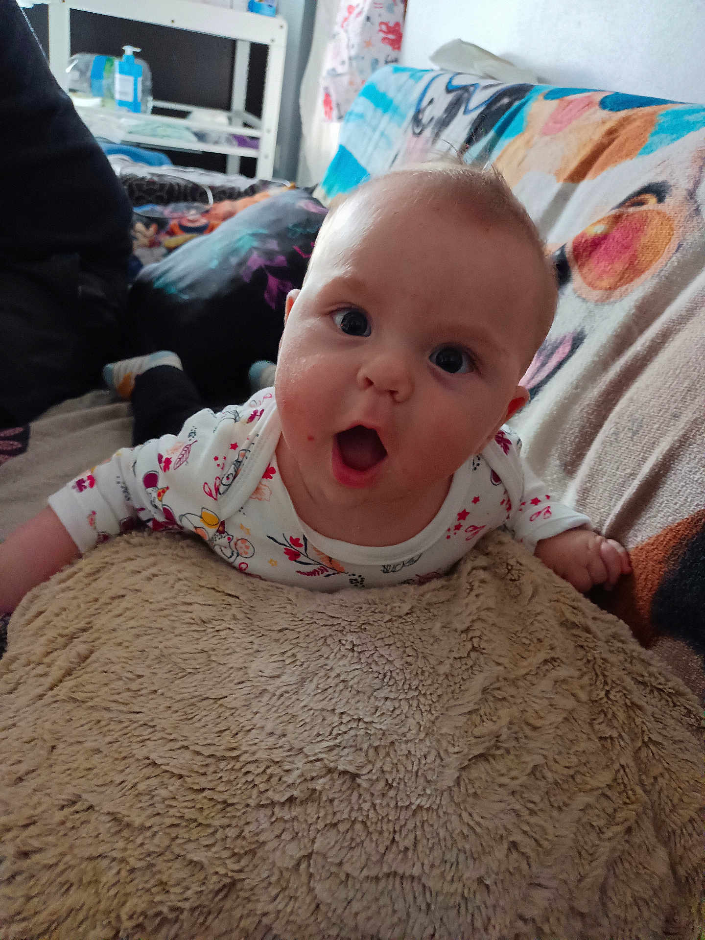 Johann a rejoint le concours — aidez-le/la à gagner de superbes lots ! baby, child, infant, couch, blanket, pillow, face, expression, wide_eyes, mouth_open, clothing, indoor, furniture, person, hand, head, soft_texture, colorful, home, background