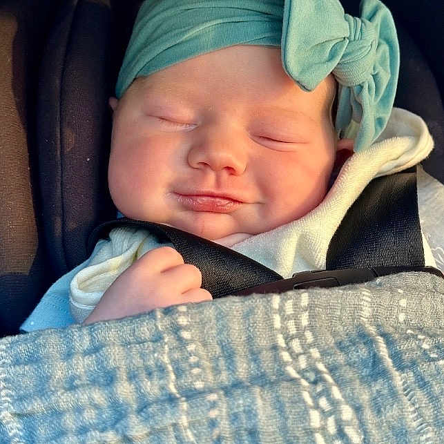 Maisie is registered to the contest to win money with this photo: newborn, baby, infant, sleeping, car_seat, seatbelt, blanket, headband, bow, portrait, face, closed_eyes, pout, cozy, travel, vehicle, sunlight, indoors, sitting, child