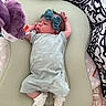 newborn, baby, infant, child, portrait, lying_down, baby_nest, onesie, bow_headband, teal, mint_green, socks, plush_toy, purple_toy, nursery, cushions, blanket, indoor, sleepy, cozy