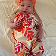 Kamiyah is registered to the contest to win money with this photo: baby, bed, blanket, child, clothing, cute, feet, floral_pattern, hands, headband, indoors, infant, light, lying_down, orange, person, portrait, romper, skin, smile