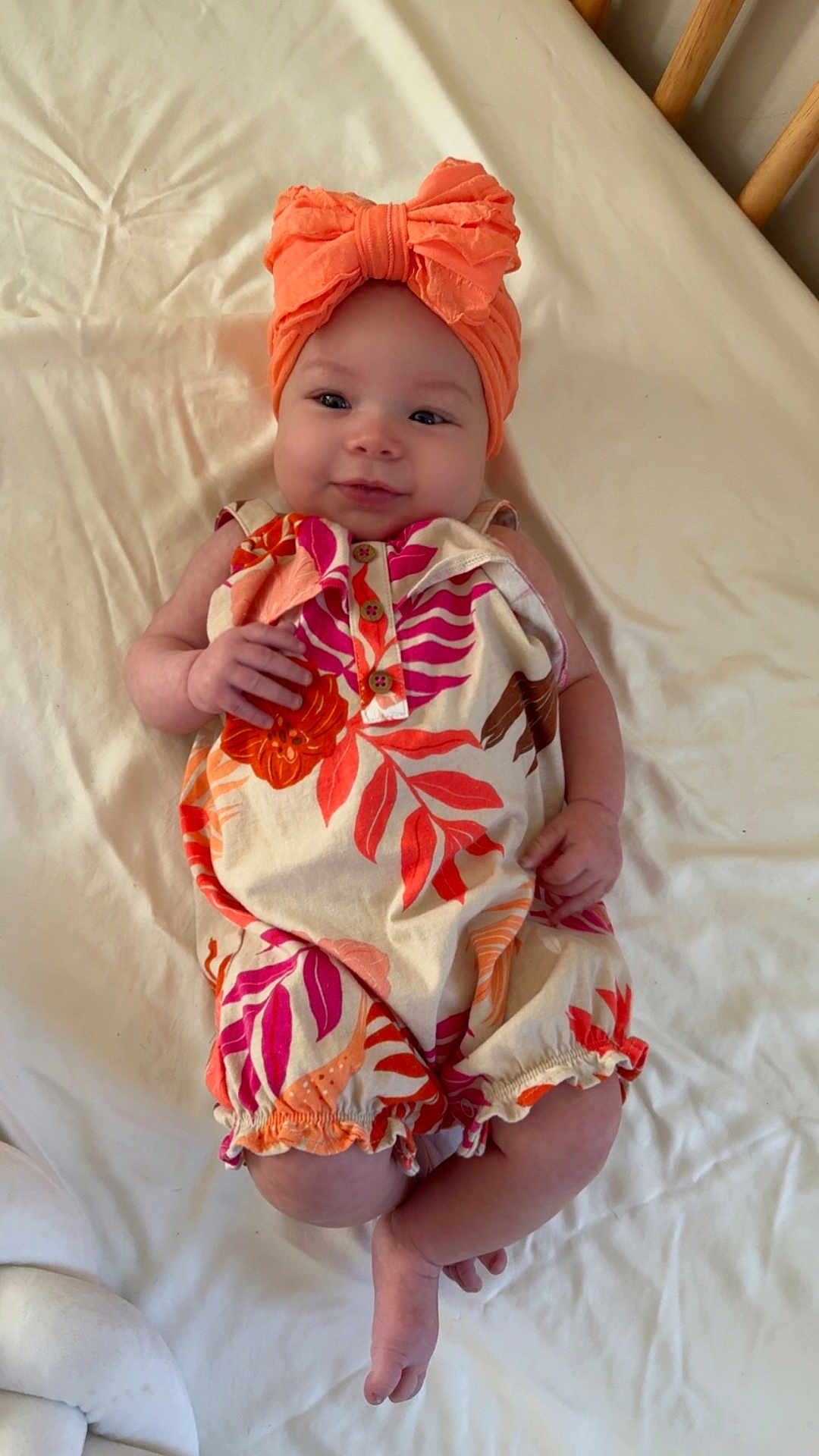 Kamiyah is registered to the contest to win money with this photo: baby, infant, child, bed, blanket, headband, orange, romper, floral_pattern, smile, cute, portrait, skin, hands, feet, clothing, indoors, light, person, lying_down