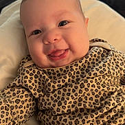 Kamiyah is registered to the contest to win money with this photo: baby, infant, smiling, face, leopard_print, clothing, cute, tongue_out, lying_down, soft_surface, happy, child, portrait, skin, head, eyes, mouth, cheeks, baby_clothes, indoor