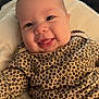baby, infant, smiling, face, leopard_print, clothing, cute, tongue_out, lying_down, soft_surface, happy, child, portrait, skin, head, eyes, mouth, cheeks, baby_clothes, indoor