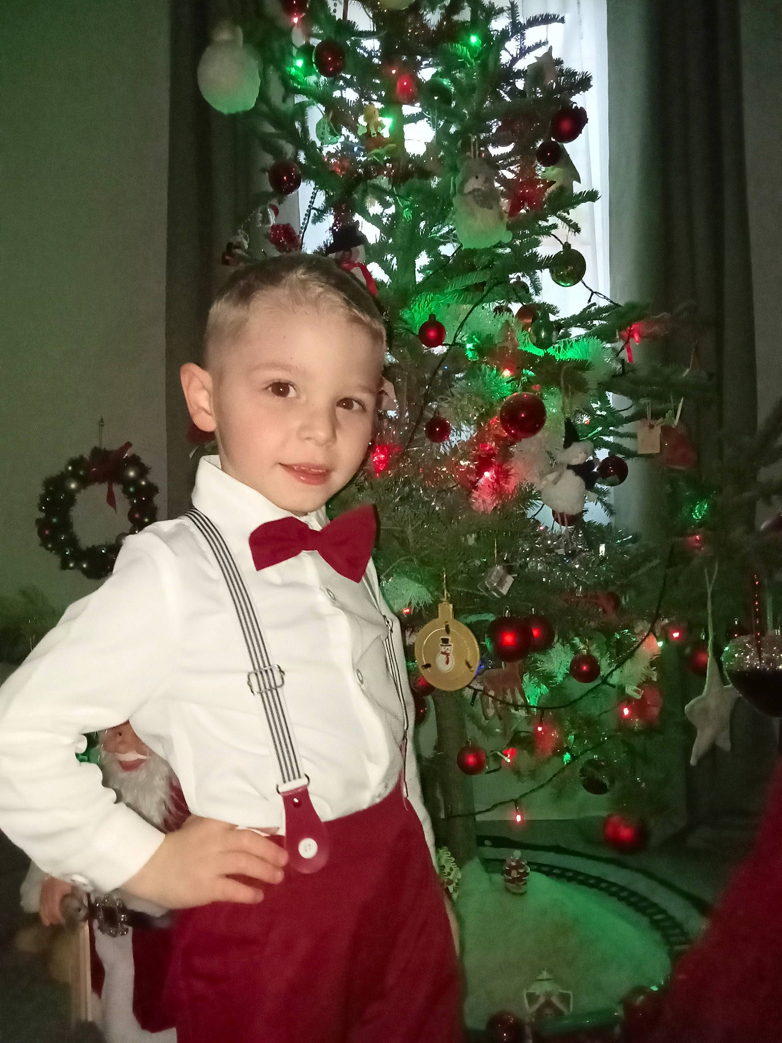 Gabriel a rejoint le concours — aidez-le/la à gagner de superbes lots ! bow_tie, christmas, christmas_decoration, christmas_ornament, christmas_tree, event, evergreen, formal_wear, happy, holiday, holiday_ornament, ornament, person, plant, red, sleeve, smile, standing, toddler, tradition