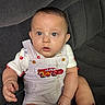 baby, child, infant, overalls, red_shoes, couch, seated, cute, portrait, wide_eyes, plump_cheeks, striped_clothing, indoor, curious, casual_wear, person, young_child, comfortable, clothing, textile