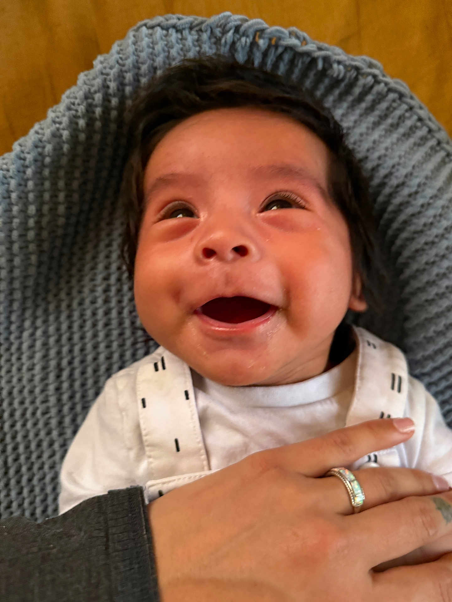 Cochise is registered to the contest to win money with this photo: baby, child, closeup, cozy, cute, expressive, face, hand, happy, indoor, infant, knitted_blanket, looking_up, person, portrait, smiling, tender, warm, white_clothing, young