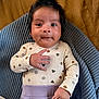 baby, child, clothing, cozy, curious, cute, face, hand, head, indoors, infant, knitted_blanket, lying_down, patterned_shirt, person, portrait, purple_pants, smiling, soft_texture, young