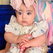 Sophia joined the competition — help win amazing prizes! baby, child, infant, headband, pink_bow, clothing, sitting, toy, beaded_toy, couch, blanket, indoor, portrait, cute, curious, person, face, hands, colorful, soft_lighting