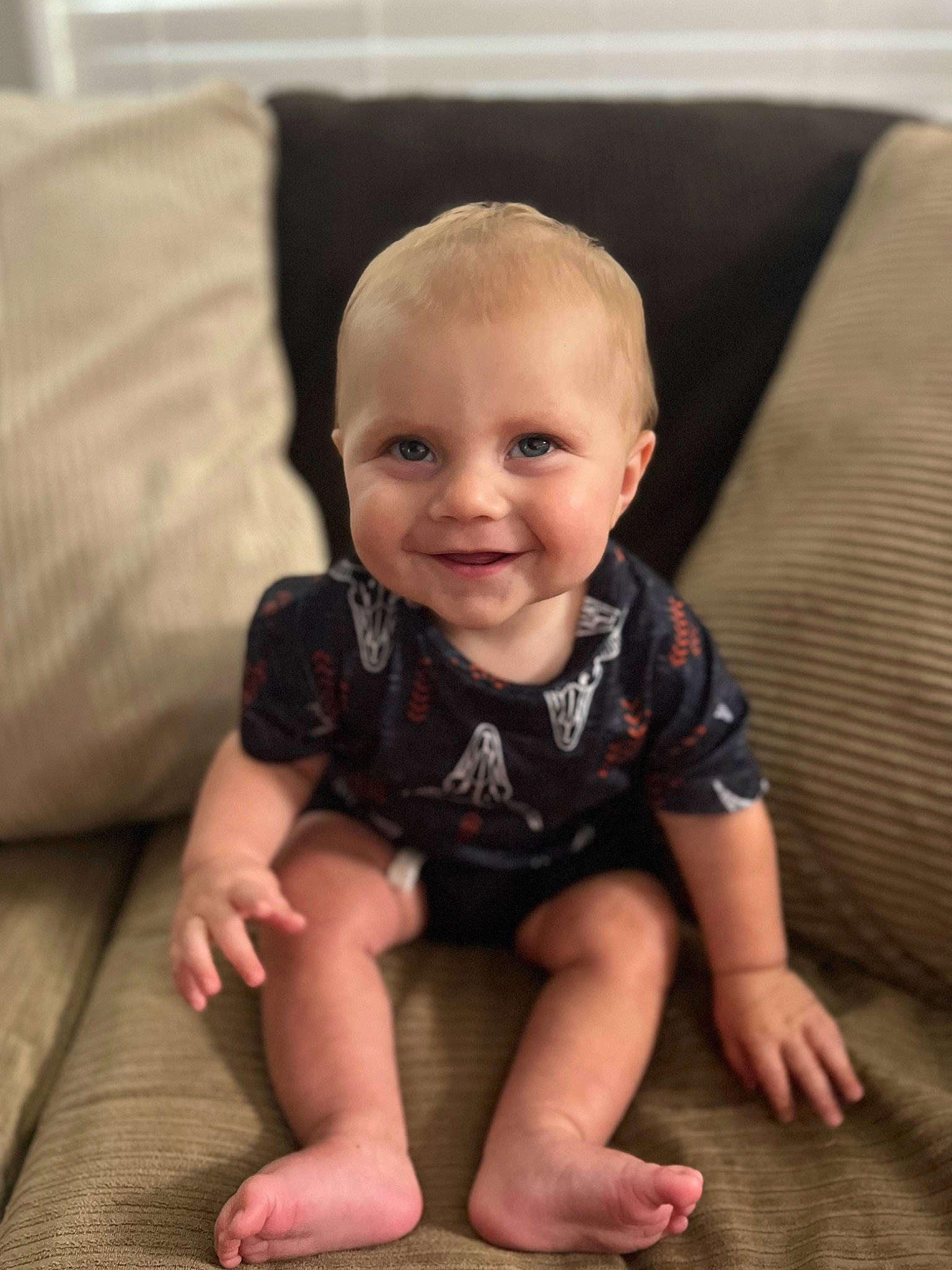 Tate joined the competition — help win amazing prizes! baby, baby_toddler_clothing, cheek, chin, comfort, couch, eye, facial_expression, floor, flooring, fun, head, iris, joy, leg, person, sitting, skin, sleeve, smile