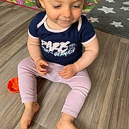 Celeyne a rejoint le concours — aidez-le/la à gagner de superbes lots ! baby, barefoot, child, clothing, cute, floor, home, indoor, looking_down, pants, person, play_mat, rug, shirt, short_hair, sitting, smile, toddler, wooden_floor, young