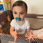 Maxmillian is registered to the contest to win money with this photo: child, baby, toddler, pacifier, playpen, onesie, hands, big_eyes, slicked_hair, toy, crib, polka_dot, blanket, indoor, portrait, drool, curious_expression, gripping_rail, face, nursery