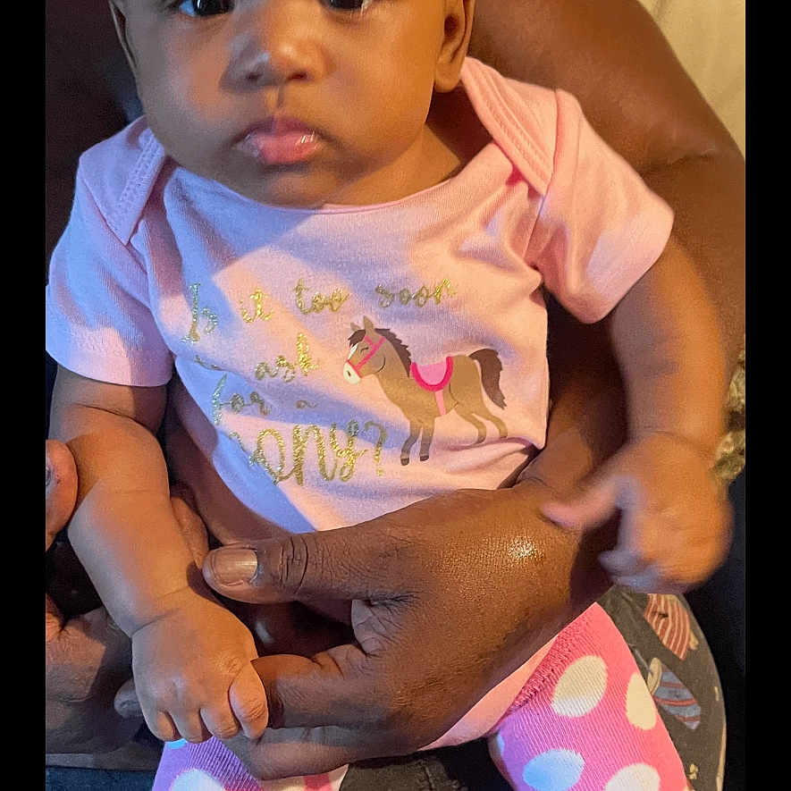 Khaliya joined the competition — help win amazing prizes! baby, child, infant, pink_clothing, polka_dot, headband, bow, sitting, person, adult_hand, couch, indoor, cute, portrait, looking_at_camera, calm, skin, clothing, pattern, holding
