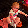 baby, child, infant, sitting, portrait, blue_eyes, blond_hair, smiling, indoor, chair, blanket, socks, shirt, orange_blanket, furniture, home, fan, water_bottle, colorful, date_stamp