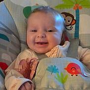 Liliana is registered to the contest to win money with this photo: animal_print, baby, baby_seat, bird, child, clothing, couch, cushions, cute, happy, indoor, infant, living_room, monkey, person, portrait, sitting, smiling, straps, young