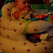 Liliana is registered to the contest to win money with this photo: baby, infant, child, sitting, activity_seat, inflatable_chair, toy, colorful_toys, portrait, face, looking_sideways, indoors, living_room, warm_lighting, low_light, phone_screenshot, lock_screen, clock, blanket, safe