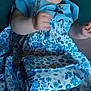baby, child, smiling, blue_dress, floral_pattern, purse, happy, sitting, cute, innocent, portrait, indoor, soft_lighting, person, young_child, joyful, clothing, accessory, cheerful, baby_girl