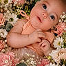 baby, infant, flower_bed, roses, daisies, pink_flowers, white_flowers, greenery, portrait, cute, child, newborn, soft_lighting, nature, floral_arrangement, skin, hands, face, smile, peaceful