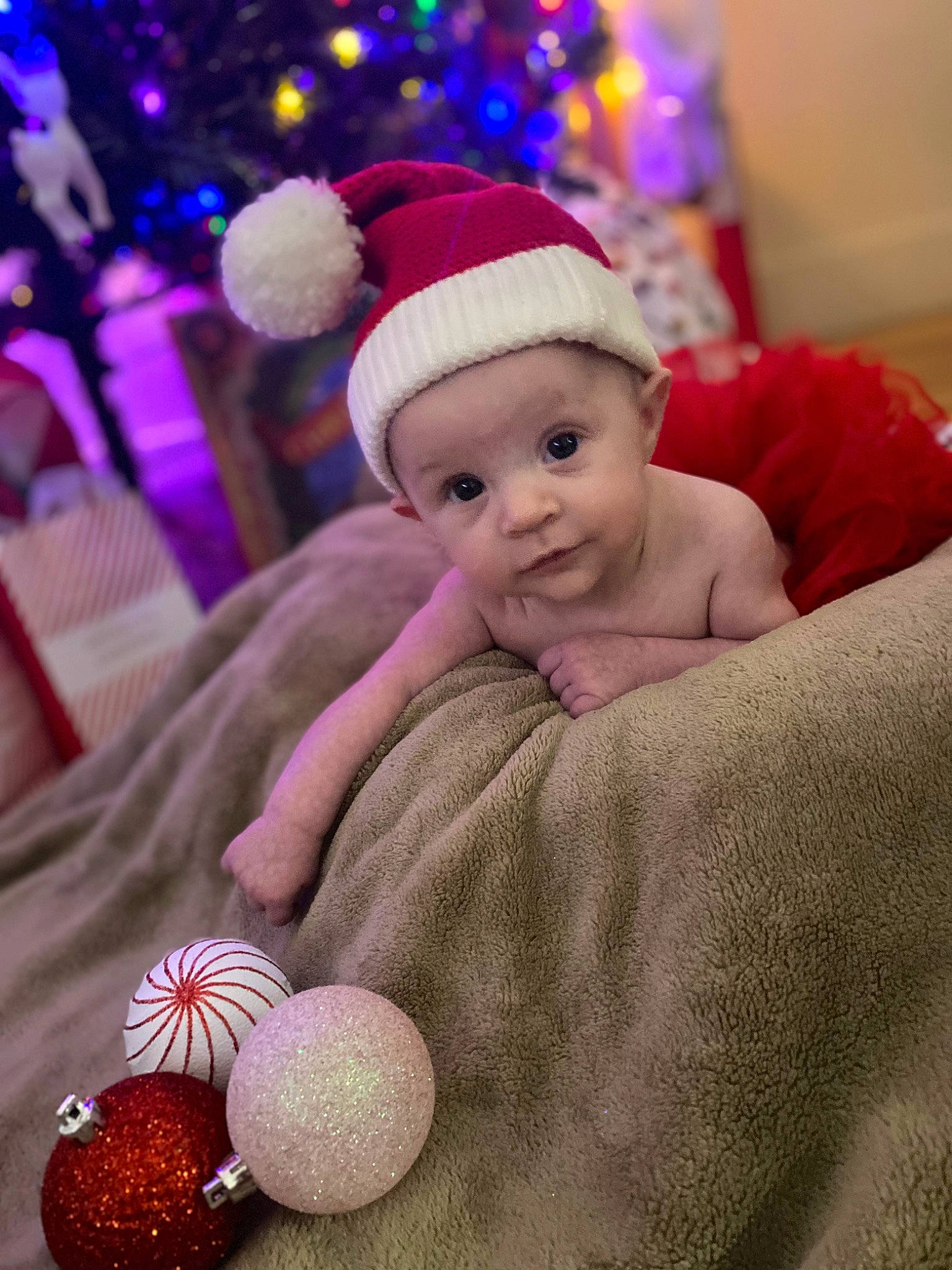 Lainey is registered to the contest to win money with this photo: baby, baby_toddler_clothing, cap, christmas, christmas_decoration, christmas_ornament, costume_hat, event, face, fun, happy, headwear, holiday, magenta, ornament, person, pink, plant, purple, textile